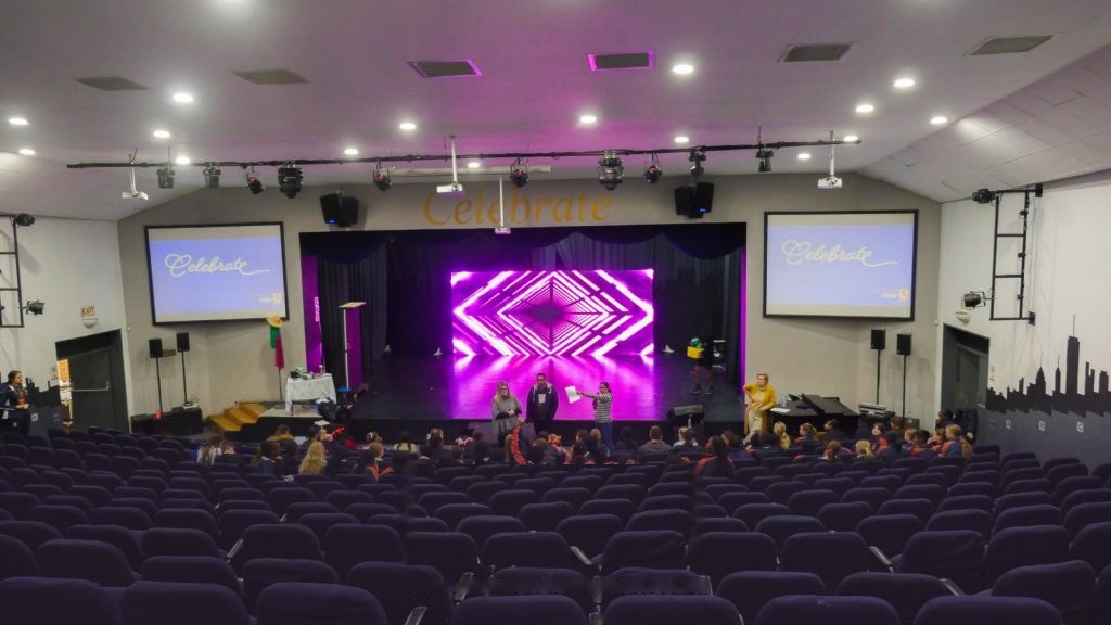 School auditorium with LED stage screen and dual projector screens